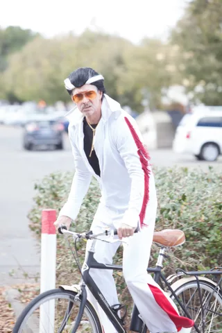 A rider in a white and red outfit pedals along the roadside.