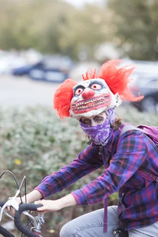A masked rider in a plaid shirt looks down at the handlebars.