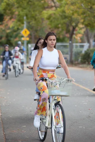 A rider in floral leggings pedals a bike with a flower-filled basket along the path.