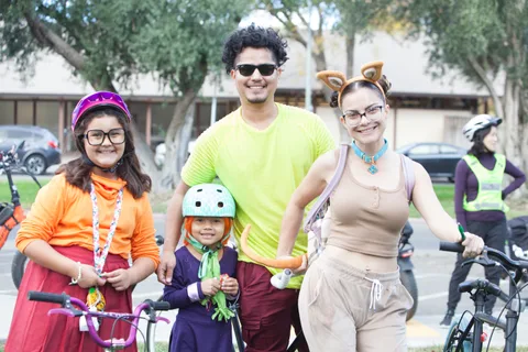 A family group poses together in the park, one child wearing cat-ear glasses.