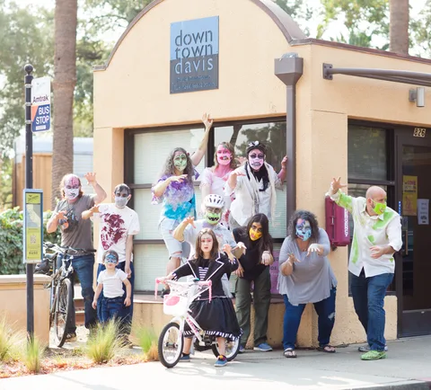 A zombie horde of riders poses under the Downtown Davis Business Association sign.