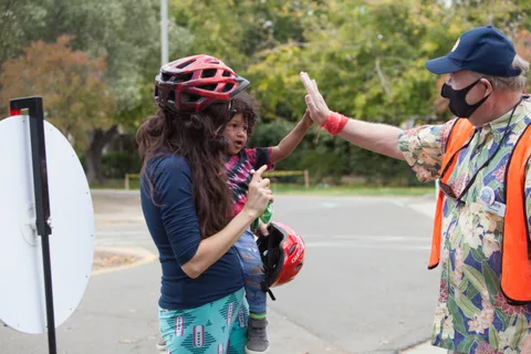 Two people high five in the street.