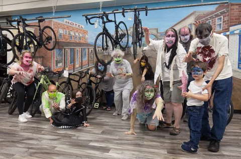 A costumed family group poses playfully in front of a colorful mural.