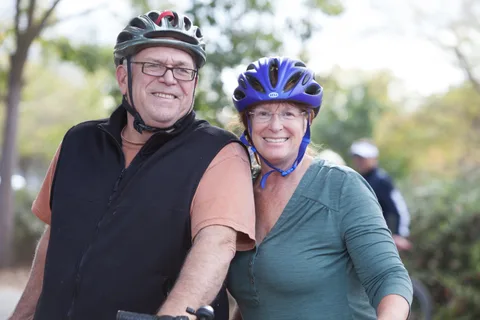 Two riders in colorful jackets pose together on their bikes.
