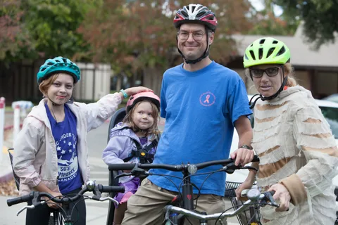 A family poses on bikes, the mother dressed as a mummy and a daughter with zombie makeup.