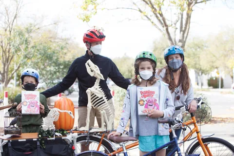 A family stands with a cargo bike decorated with skeleton figures and a pumpkin.