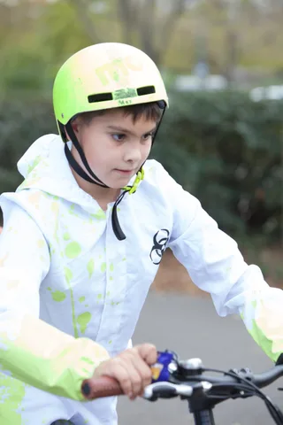 A child in a bright green helmet looks seriously at the camera in close up.