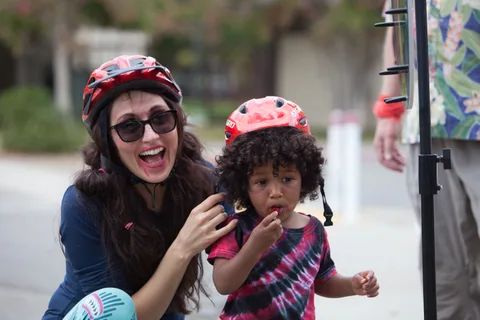 A laughing woman shares a candid moment with a child in tie-dye.