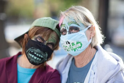 Two women in painted masks stand close together.