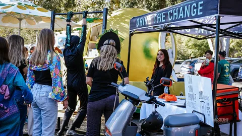 A volunteer hands out food from a branded cart in the park.