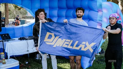 Two young men hold up a DJ Mellax flag beneath an inflatable octopus display.