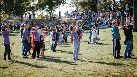 A costumed crowd stands together watching the sky during the skydiving finale.