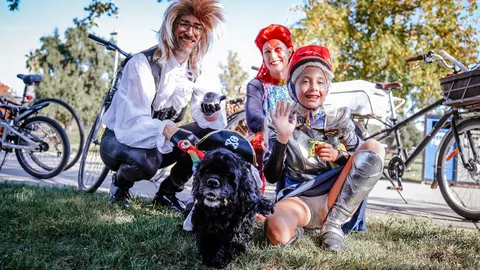 A costumed group with wild wigs poses with their dog beside their bikes.