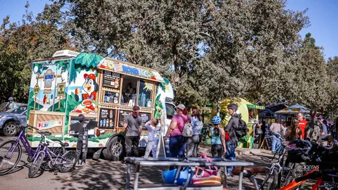 A colorful food truck serves a line of festival-goers.