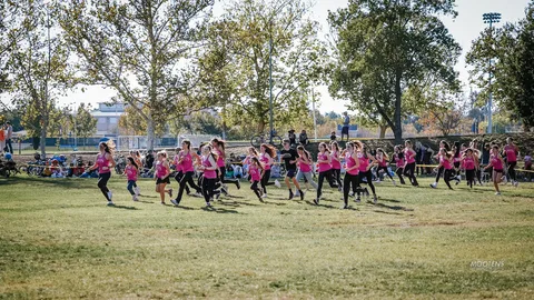 A wide view of the dance team performing near the tree line.