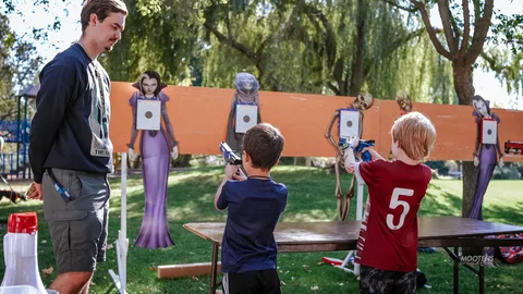 A boy aims a laser pistol at a cutout target.