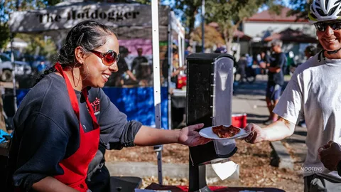 A vendor hands a plate of food to a festival-goer in sunglasses.