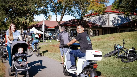 A man rides a white electric scooter down a park path.