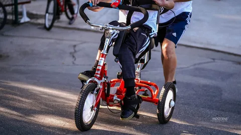 A close view of a rider pedaling a red adaptive trike.