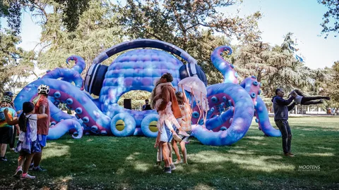 Festival-goers walk near a large inflatable octopus display.