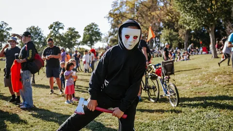 A person in a white hockey-style mask holds a prop axe.