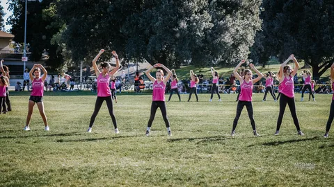 A youth dance team performs a synchronized move on the field.
