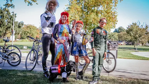 A costumed family waves together with their dog and bikes.