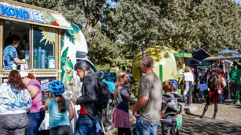 A line of people wait to order at a colorful food truck.
