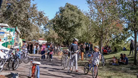 A wide view of festival-goers with bikes along the vendor path.