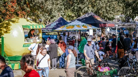 Festival-goers browse a row of vendor tents beneath a giant inflatable lemon.