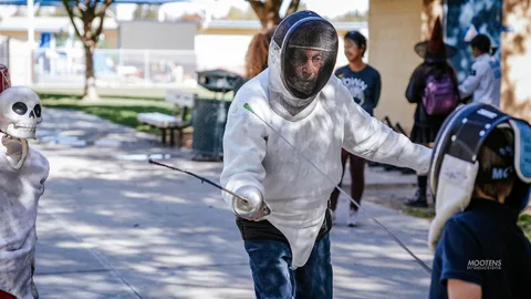 A fencer lunges forward, face hidden behind a wire mesh mask.