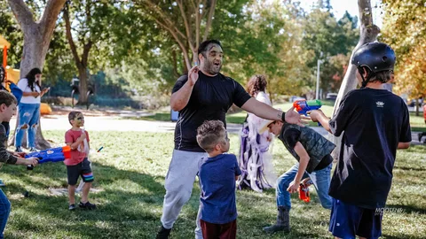 A family plays with water guns in the park.