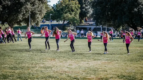 A youth dance team performs together on the open field.
