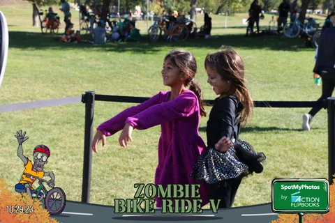 Two girls in witch and zombie costumes reach toward the camera playfully.