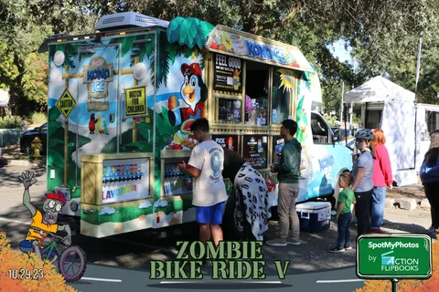 A colorfully painted snack truck serves festival guests under the trees.