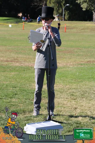 A person's legs and shoes stand near a white pedestal on the grass in an odd headless crop.