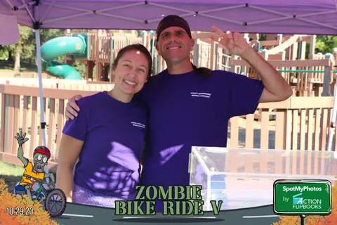 Two festival staff members in matching purple shirts pose together.