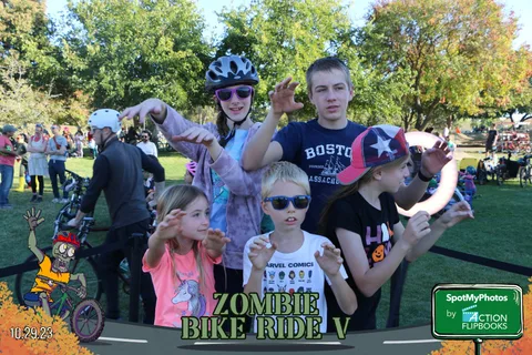 A group of kids and teens pose together near their bikes.