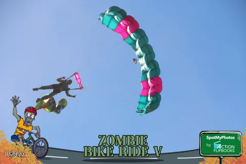 A skydiver descends under a colorful canopy holding a small flag.
