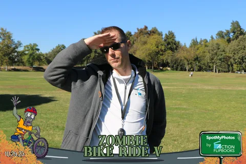 A man shades his eyes while standing in the open park.