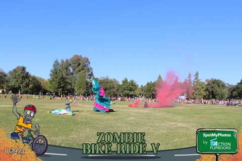 A wide view of the grassy field with a small distant figure landing under a parachute.