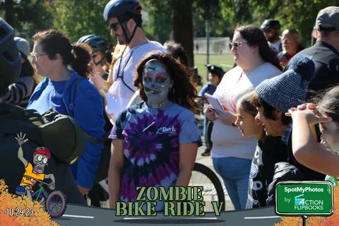 A face-painted performer in a tie-dye shirt stands amid the crowd.