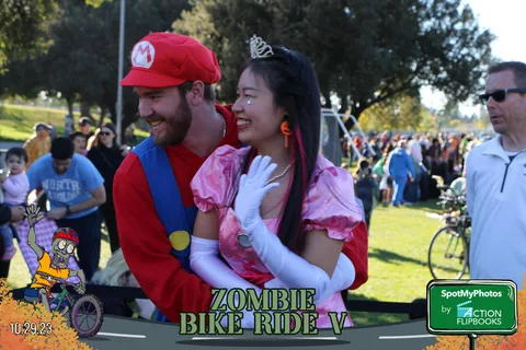 A couple dressed as Mario and a princess smile together in the crowd.