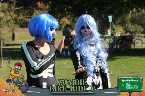 Two women in matching blue wigs and skeleton makeup strike a playful pose.