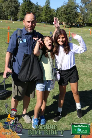 A man in a blue jacket waves alongside two excited girls.