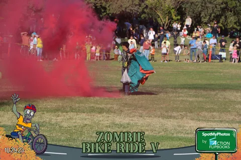 A skydiver lands amid a large red smoke plume as the crowd watches.