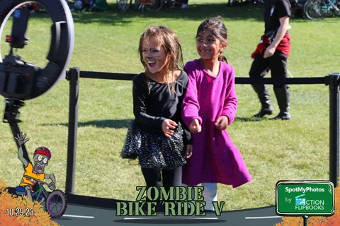 Two girls in pink and black dresses smile together at the festival.