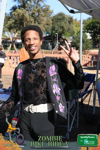 A man in a floral shirt gives a peace sign near the playground.