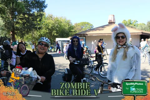 A group of costumed cyclists, including a white bunny costume, ride together.