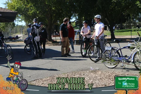 Cyclists stand with their bikes near the park gazebo.